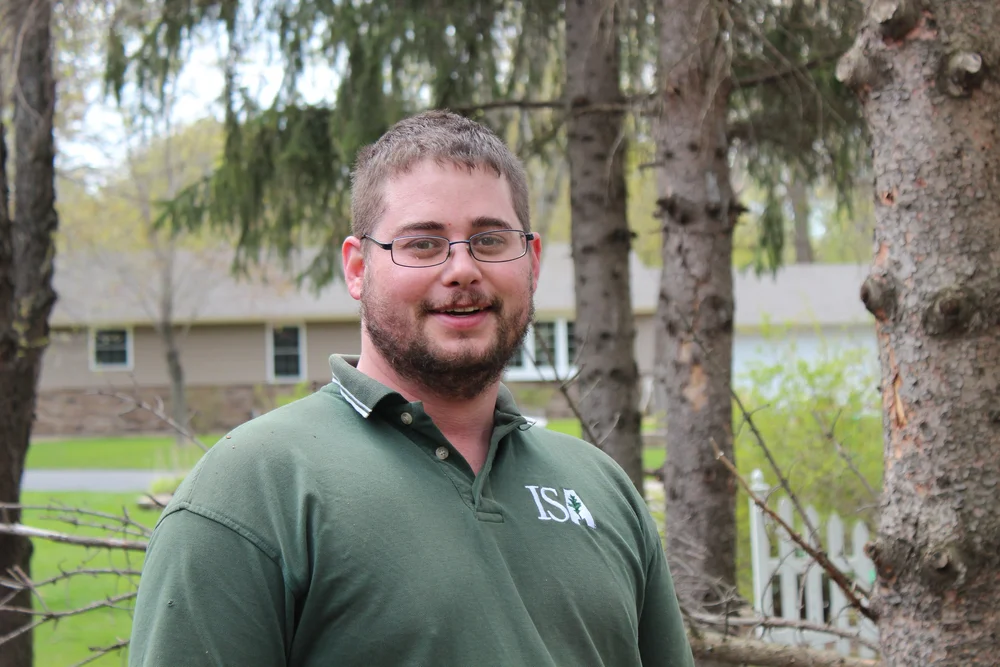 Josh, owner of True Tree Solutions and ISA Certified Arborist, in front of trees on a job site